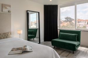 カスカイスにあるBreeze Apartment by Olala Homesのベッド1台と緑の椅子2脚が備わるホテルルームです。