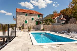 a villa with a swimming pool in front of a house at Biokovski zagrljaj in Zagvozd