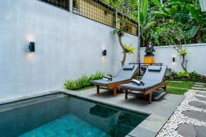 un patio avec deux chaises et une piscine dans l'établissement Umah Asri, à Ubud