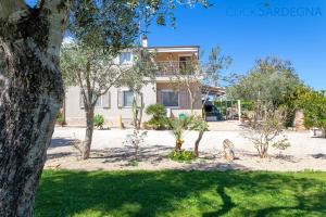 una casa con muchos árboles delante de ella en ClickSardegna Villa dei Limoni with pool close to the beach, en Fertilia