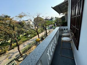 een balkon met 2 stoelen en uitzicht op een straat bij Cosy 2 Homestay in Hue