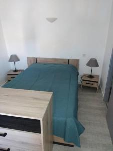 a bedroom with a bed with a green blanket at Le porche in Moissac-Bellevue