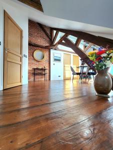 a living room with a vase of flowers on a wooden floor at Les Bulles d'Aÿ - Loft in Ay +10 photos