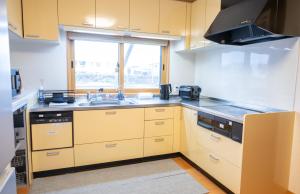 a kitchen with yellow cabinets and a sink and a window at House Villa Kagura in Asahikawa +75 photos