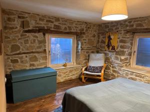 a bedroom with stone walls and a bed and a chair at Ta Petrina Cottage in Selishte