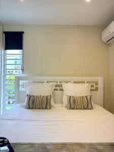 Un dormitorio con una cama blanca con dos almohadas. en Hana Mana Bungalow - Magnifique Piscine, Plage à 100m, en Grand-Bourg