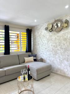 een woonkamer met een bank en een tafel bij Hana Mana Bungalow - Plage proche, Grande Terrasse in Grand-Bourg