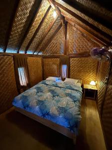 a bedroom with a bed with a blue comforter at Padi Bungalow in Tetebatu