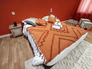 a large bed with an orange comforter in a bedroom at Studio Chic N2 avec Jacuzzi in Roubaix