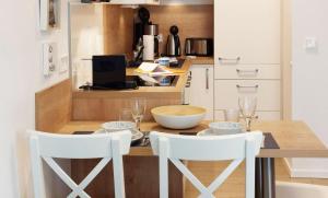 a kitchen with a wooden table with two white chairs at Baabe Villen-Ensemble FeWo 41 Muschelsucher in Baabe +8 photos