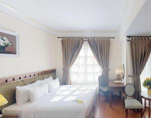 a hotel room with a bed and a desk and a window at Phoenix Hotel Vung Tau in Vung Tau