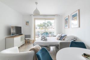 a room with a bed and a tv and chairs at Le Colombe - Centre de La Baule - Wifi in La Baule