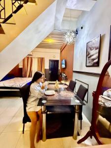 a woman sitting at a table in a room at Axon Cozy Modern House G Near The Walking Street in Angeles