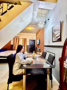 a woman sitting at a table in a room at Axon Cozy Modern House G Near The Walking Street in Angeles