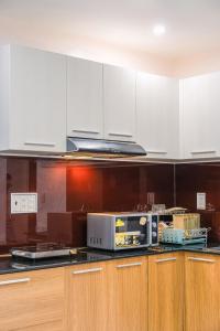 a kitchen with white cabinets and a microwave at Ami Villa Dalat in Da Lat