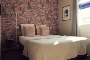 a bedroom with a large bed with pink walls at Hôtel Azur in Reims