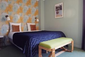 a bedroom with a bed with a blue blanket and a bench at Hôtel Azur in Reims
