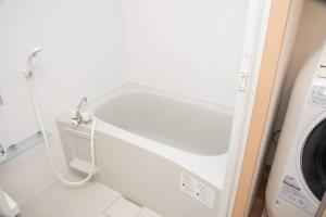 a white tub in a bathroom next to a washing machine at レーヴk402 in Makishimachi +19 photos