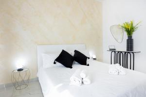 a white bedroom with a white bed with black pillows at A due passi in Capri