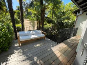 un banco sentado en una terraza de madera con árboles en Ascona Casa Azzurra, en Ascona