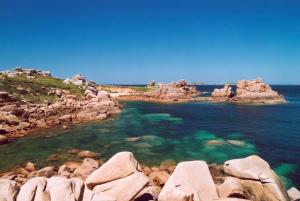 a rocky shore with clear blue water and rocks at Terrasse charme & nature en coeur de Lannion in Lannion