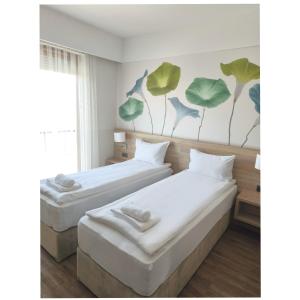 two beds in a room with green leaves on the wall at Family-Hotel in Balástya +32 photos