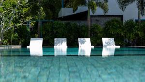 4 sillas blancas sentadas junto a una piscina en Villa Lila, en Ko Lanta