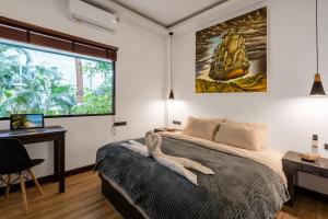 Un dormitorio con una cama y un escritorio y una ventana. en Villa Lila, en Ko Lanta