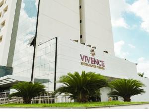 Un gran edificio blanco con palmeras delante. en Flat em Palmas Vivence Suítes, en Palmas