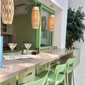 a kitchen with a bar with green chairs and chandeliers at Villa Verde Sidi Bou Said in Sidi Bou Saïd