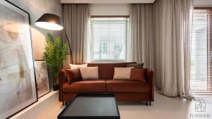 un salon avec un canapé marron et une table dans l'établissement Flatbook - Studio Yacht Park Gdynia, à Gdynia