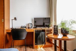 エアフルトにあるHotel Gartenstadt Erfurtのデスク、テレビ、テーブルが備わる客室です。