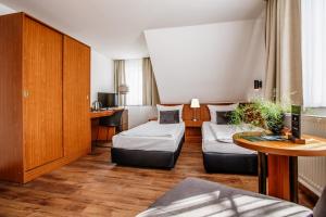 エアフルトにあるHotel Gartenstadt Erfurtのベッド2台とテーブルがあるホテルの部屋