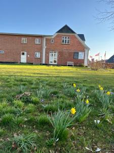 a field of flowers in front of a brick building at Gæstehusets lejlighed in Tarm +4 photos