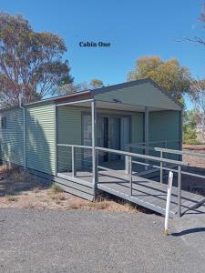 MinyipMinyip Caravan Park的绿色的组合式房屋,设有门廊和栏杆