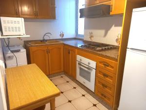 a small kitchen with wooden cabinets and a sink at Victoria, 8-22 in Cullera