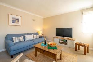 Una sala de estar con un sofá azul y un televisor. en 3 St Johns Court - Aldeburgh Coastal Cottages, en Aldeburgh
