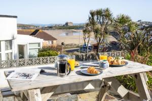 a picnic table with food and drinks and a view of the beach at Casa Sirena Apartment in Fistral, Newquay in Newquay