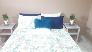 a bed with a blue comforter and two night stands at Central Cottages in Soweto