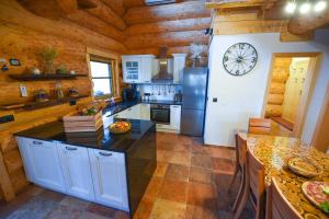 a kitchen with a refrigerator and a clock on the wall at Luxury Log House in Globoko