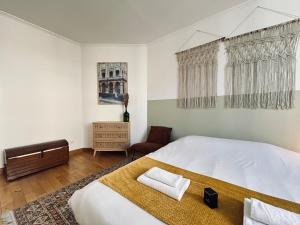 a bedroom with a large white bed and a chair at E Gambetta T3 au pied de l avenue de champagne in Épernay