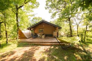 una cabaña en el bosque con una hamaca delante en Lodge Holidays - Les 3 Cantons, en Saint-Antonin