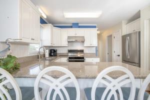 una cucina con armadi bianchi e frigorifero in acciaio inossidabile di Azure home a Emerald Isle