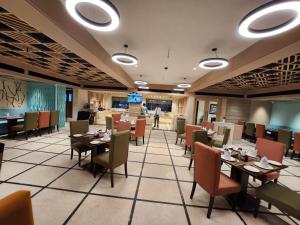 a restaurant with tables and chairs and a person in the background at The Central Park Hotel in Gwalior +43 photos