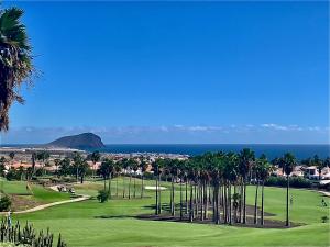 a view of a golf course with palm trees and the ocean at Golf vila3 in San Miguel de Abona