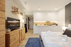 un soggiorno con TV e cucina di Apartament Premium Lux - tuż przy morzu-baseny,sauny i jacuzzi w CENIE! -Pinea Apartments Pobierowo-SANNEL Apartments for rent a Pobierowo