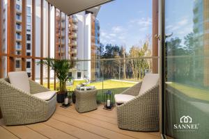 balcone con sedie in vimini e vista su un edificio di Apartament Premium Lux - tuż przy morzu-baseny,sauny i jacuzzi w CENIE! -Pinea Apartments Pobierowo-SANNEL Apartments for rent a Pobierowo
