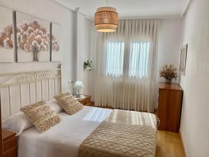 a bedroom with a white bed and a window at Balcón del atardecer in Cangas de Onís