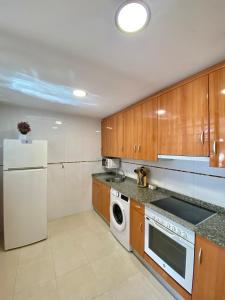 a kitchen with wooden cabinets and a white refrigerator at Balcón del atardecer in Cangas de Onís +2 photos