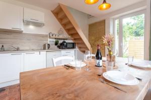 a kitchen with a wooden table with plates and wine glasses at Gîte Avec Jacuzzi Chic & Cosy entre Caen et la Mer en Normandie in Biéville-Beuville
